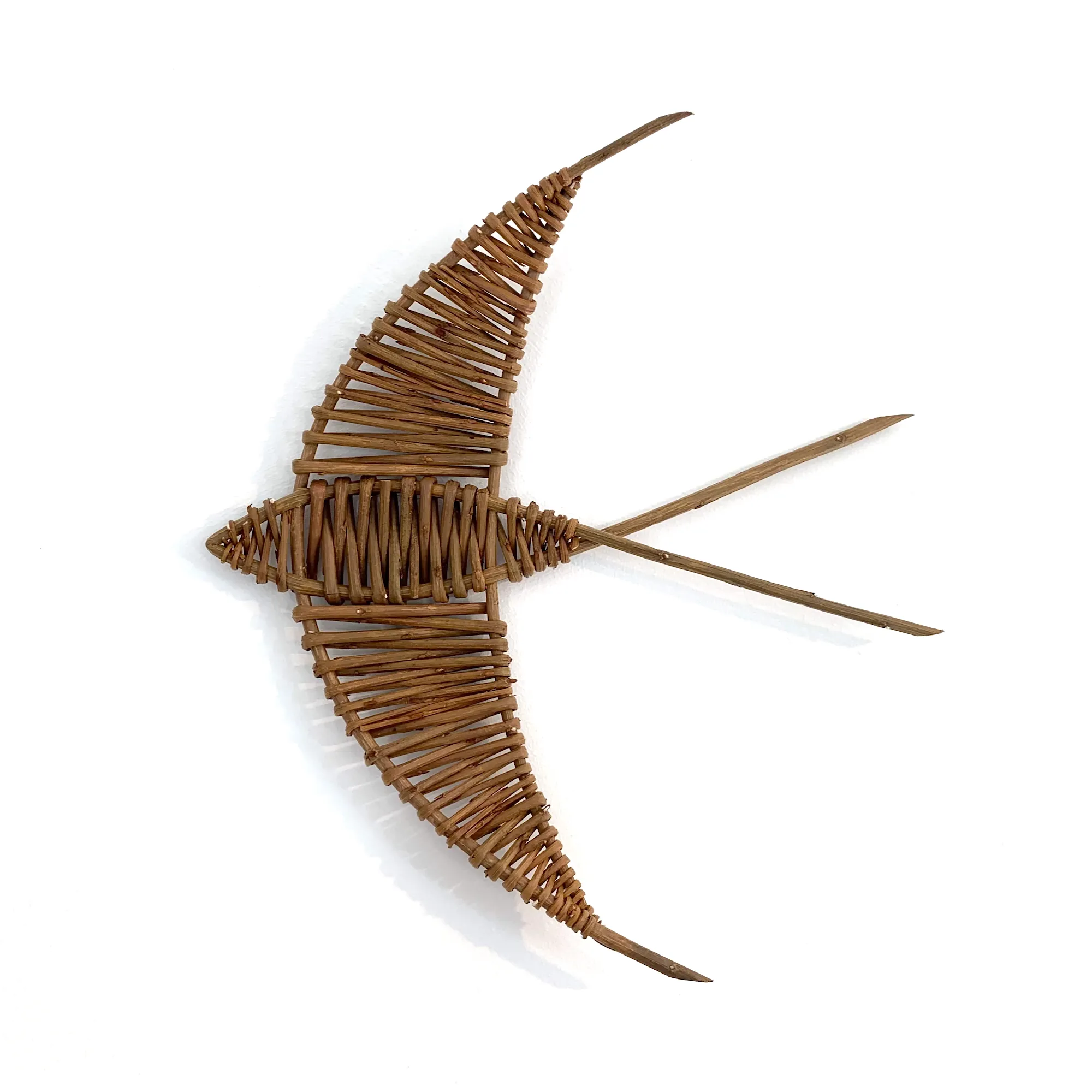 one woven willow swallow wall art hung on a white wall