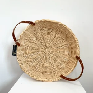 a shallow white willow basket with leather handles