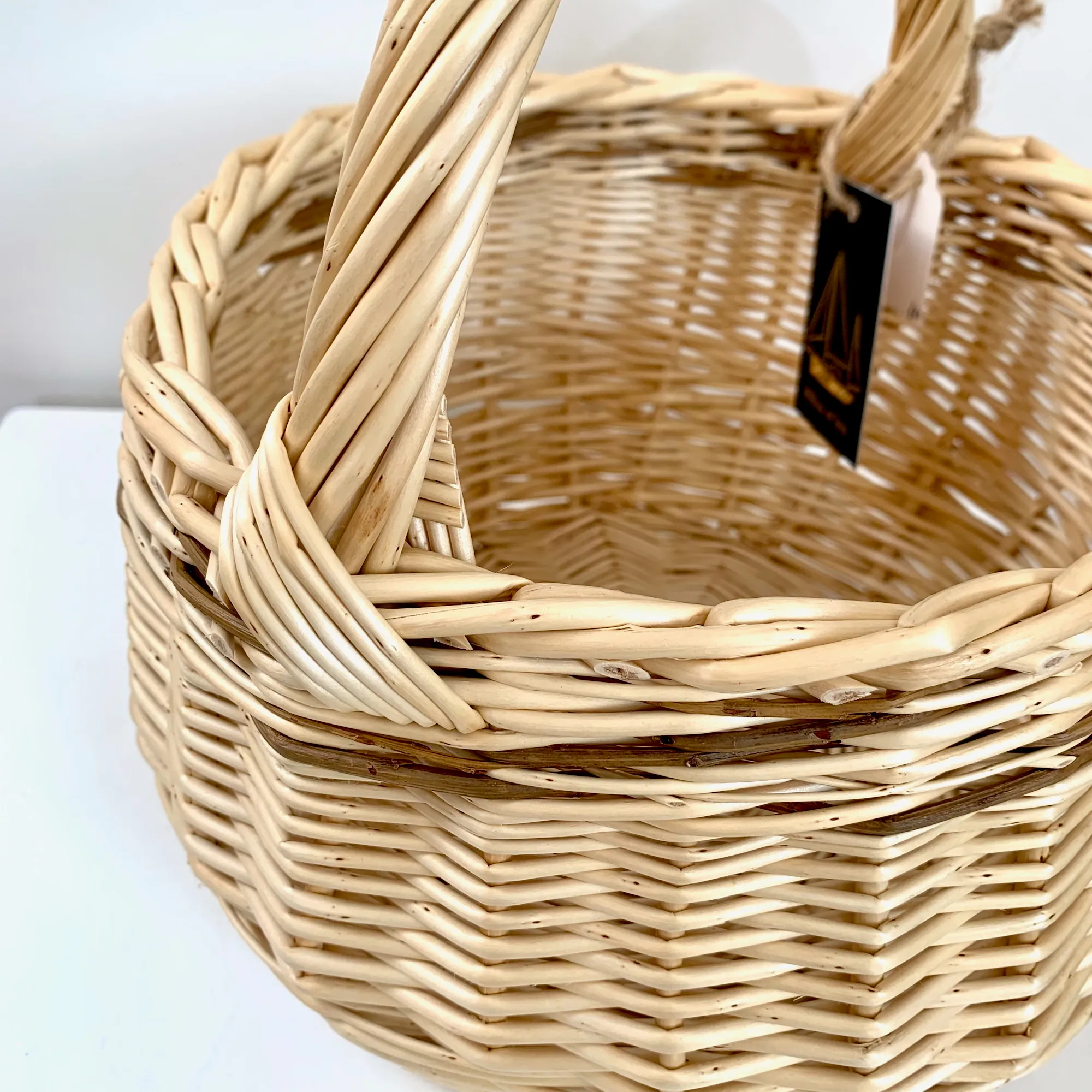 close up of the handle join on a small white willow foraging or kindling basket with brown willow woven through it also.