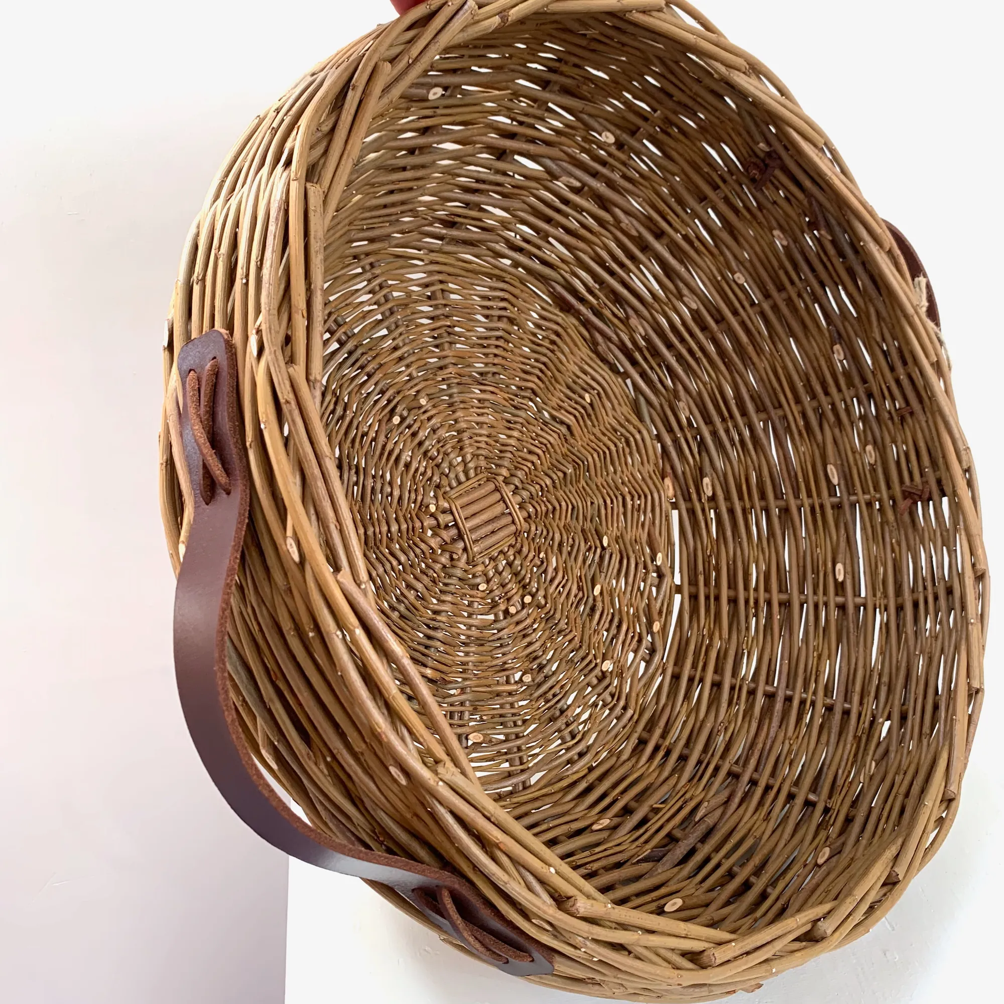 a large willow basket on its side with leather handles